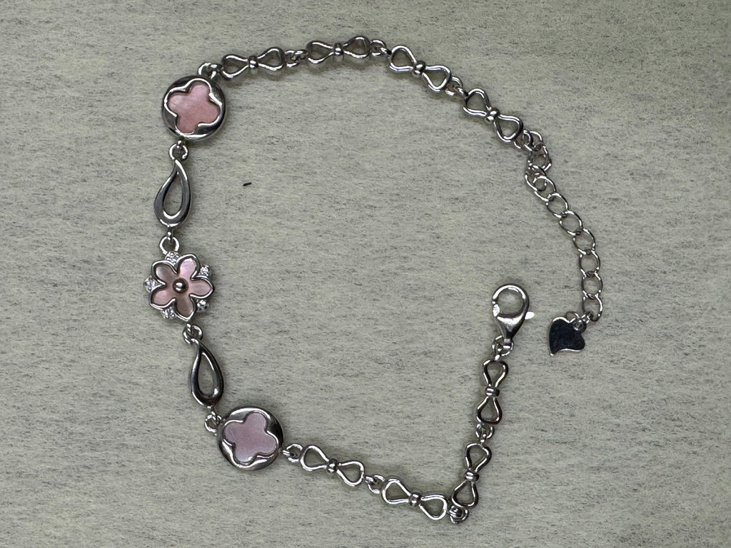 Sterling silver station bracelet laid open on a pale ground, showing the pear-shaped links between the pink stations.