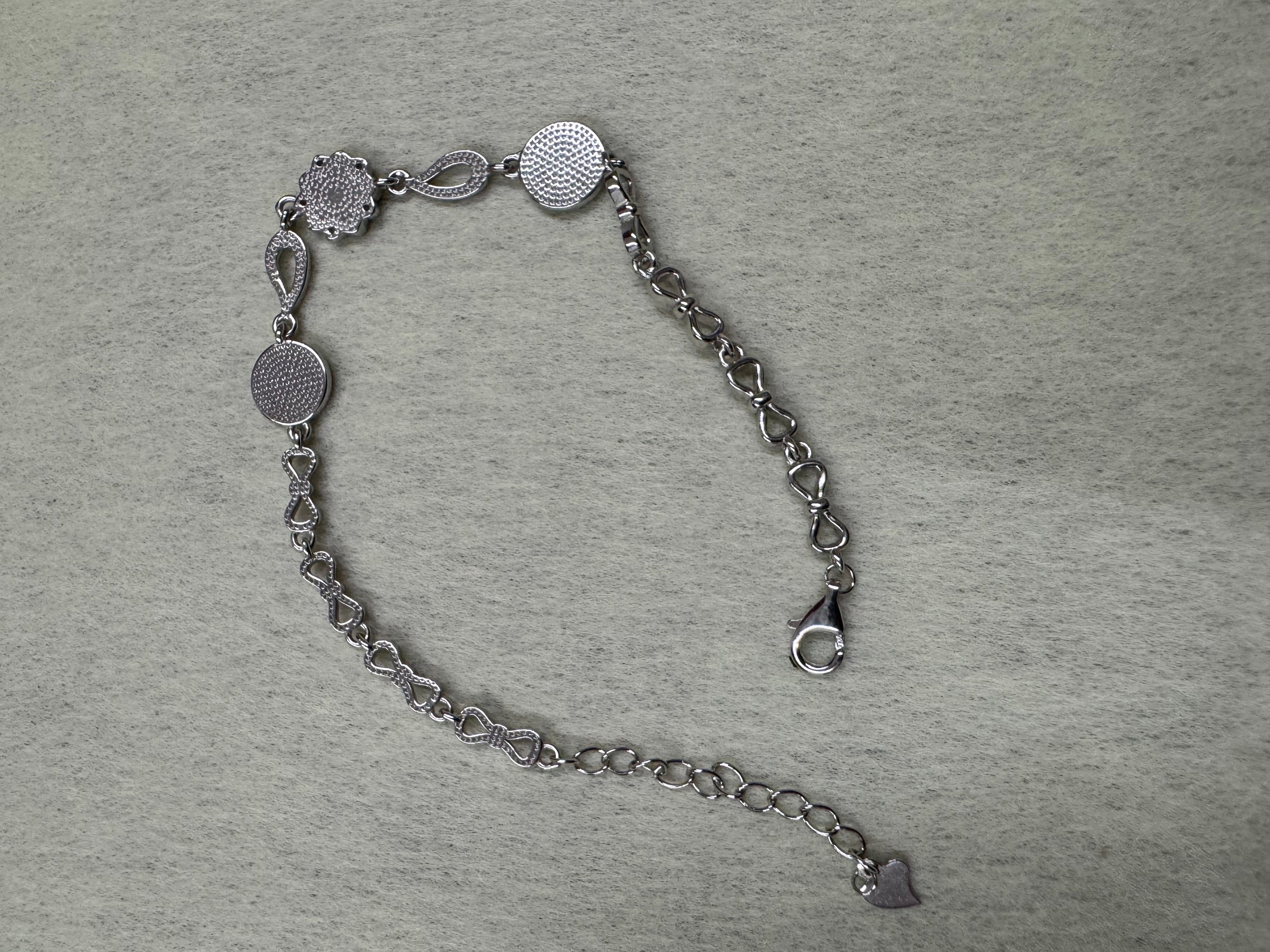Reverse of the sterling silver bracelet arranged in a curve, showing the dotted backs of the three stations.