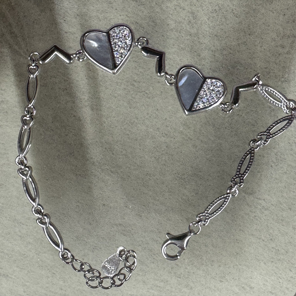 The sterling silver heart bracelet opened out on grey felt, showing the lobster clasp, extender chain and navette links.