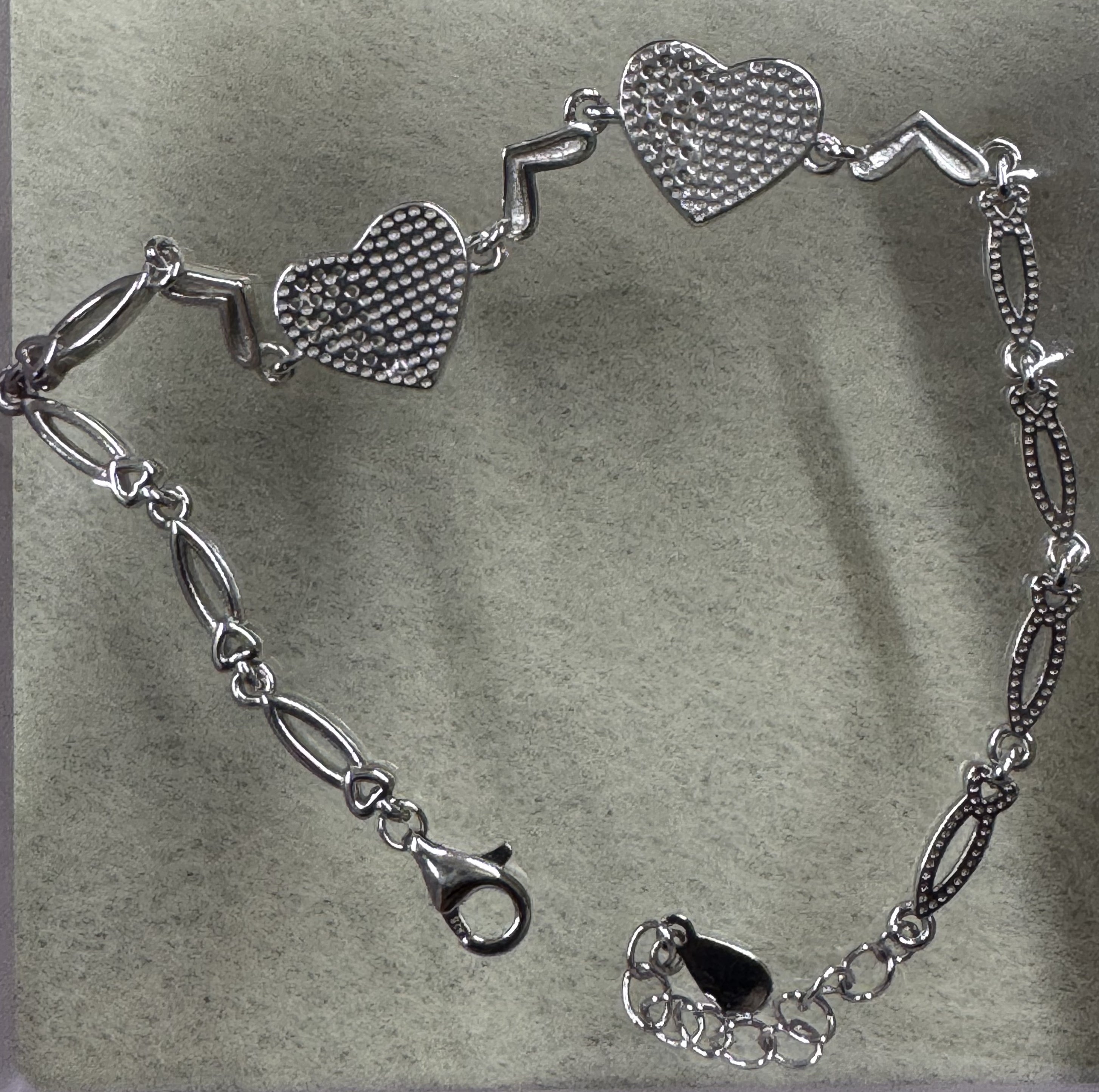 Reverse of the sterling silver heart bracelet, showing the pierced dotted backs of the two heart stations.