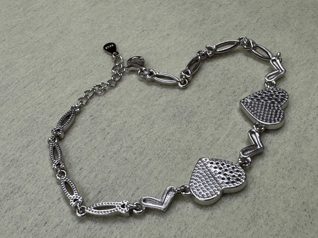 Angled view of the reverse of the sterling silver heart bracelet, showing the dotted backs and the open navette links.