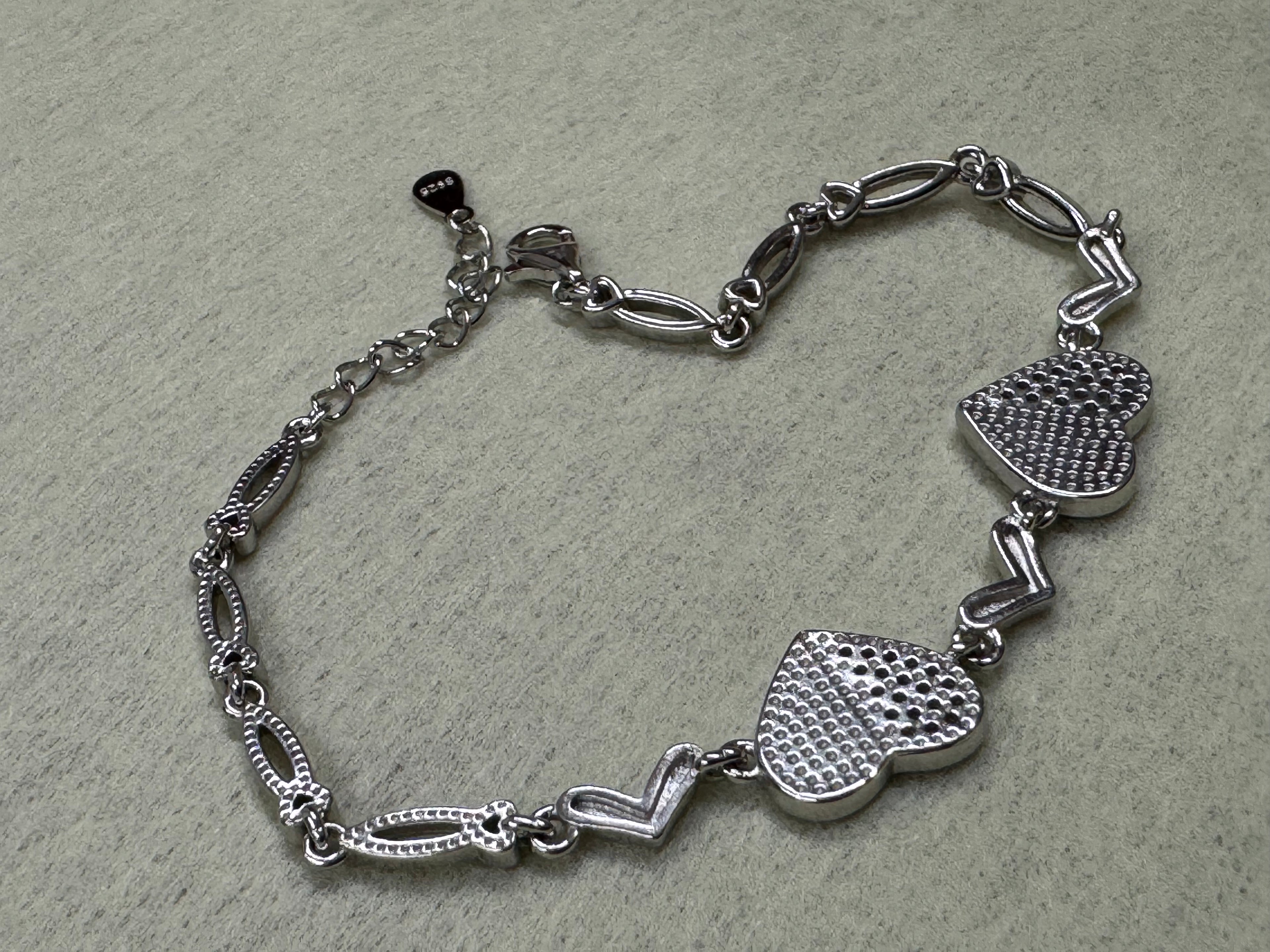 Angled view of the reverse of the sterling silver heart bracelet, showing the dotted backs and the open navette links.