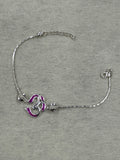 Sterling silver bracelet with a magenta enamel Om station on a fine flat chain, laid flat on grey felt.