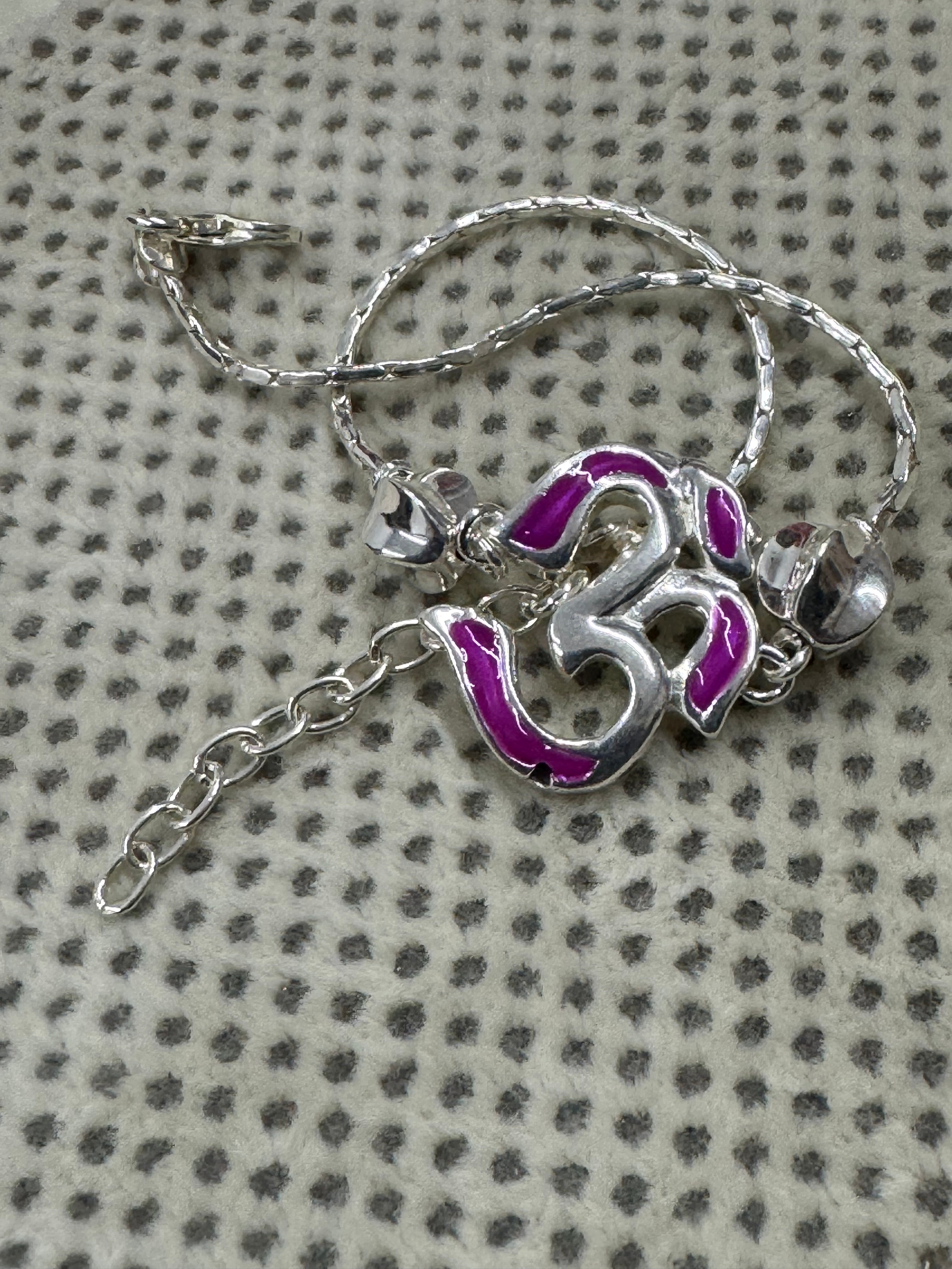 The sterling silver Om bracelet gathered on dotted cream fabric, with the extender chain trailing below.