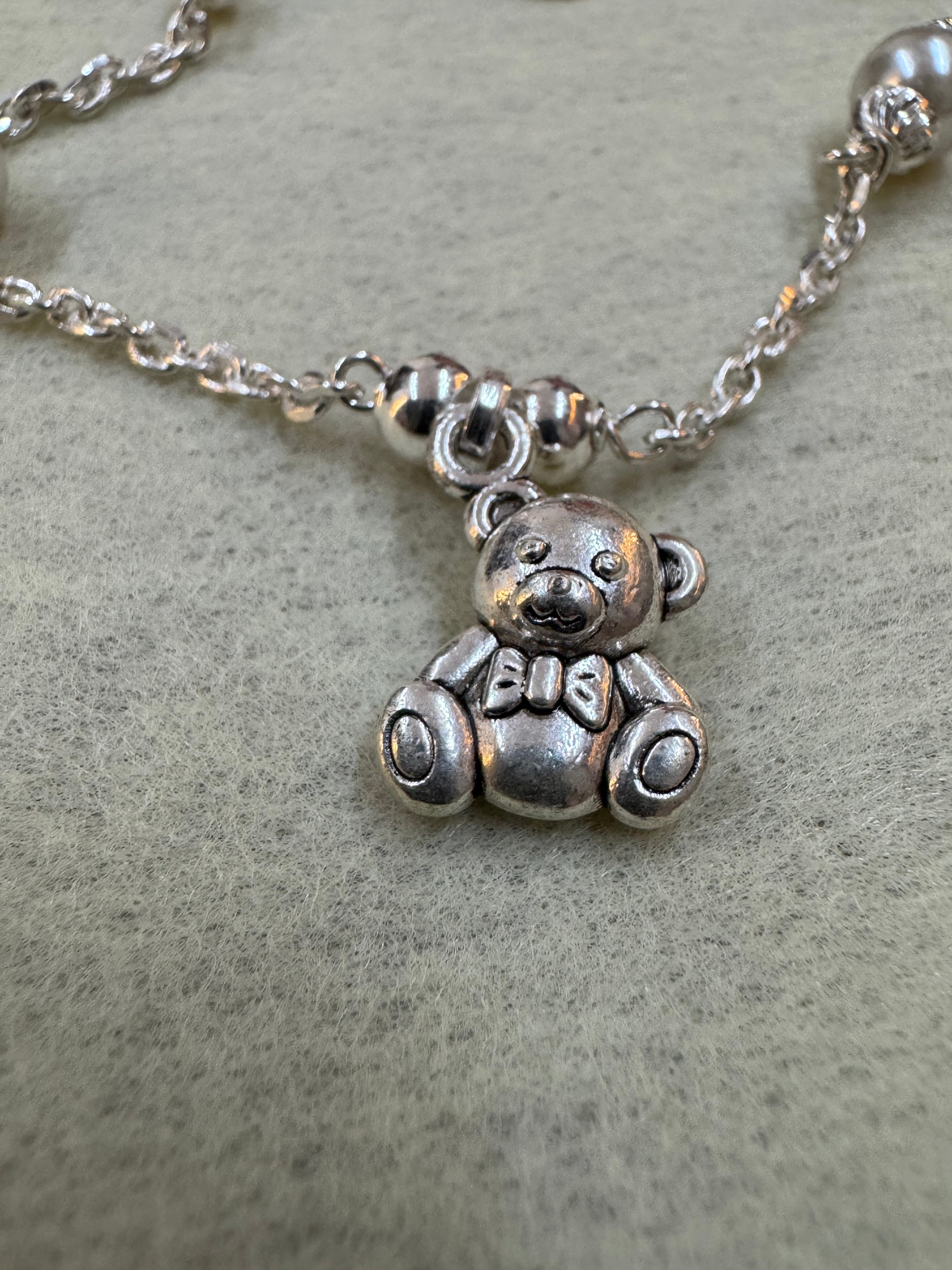 Close view of the oxidised teddy bear charm on the sterling silver bracelet, with the cable chain and round silver beads behind it.
