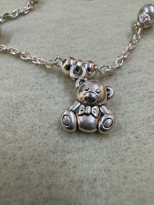 Close view of the oxidised teddy bear charm on the sterling silver bracelet, with the cable chain and round silver beads behind it.
