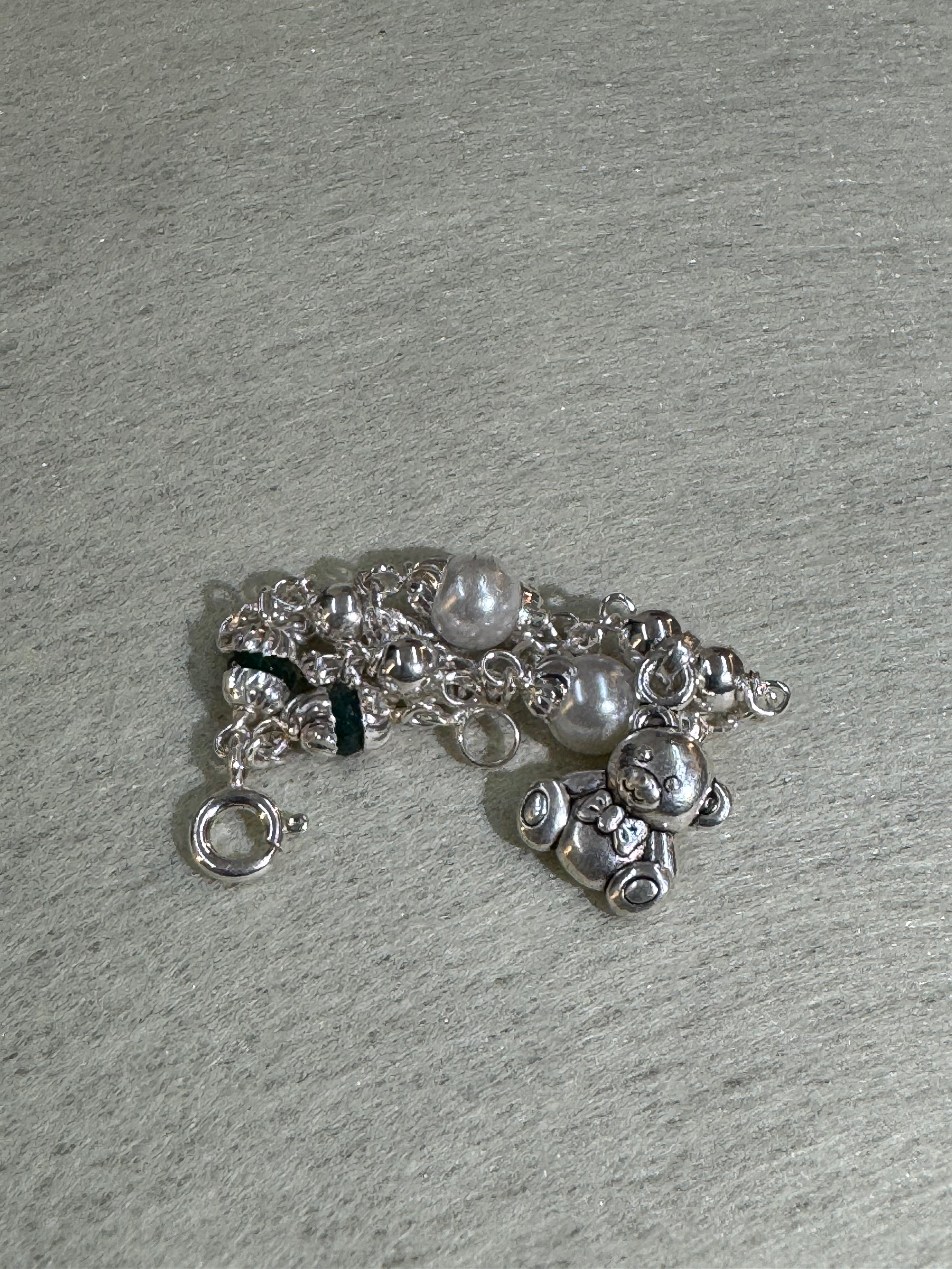 Gathered sterling silver bracelet seen from the side, showing the larger round beads and the profile of the teddy bear charm.