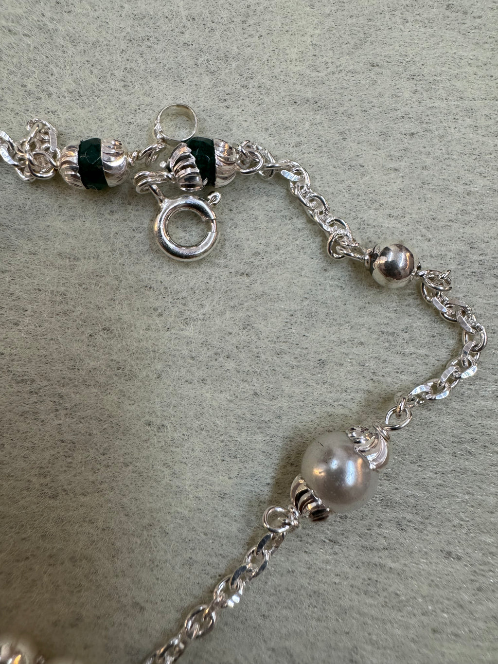 Close view of the spring ring clasp and the fluted silver beads on the sterling silver charm bracelet.