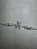 Sterling silver charm bracelet with a cast enamelled figure and faceted bead stations, laid on pale grey felt.