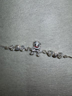Sterling silver charm bracelet with a cast enamelled figure and faceted bead stations, laid on pale grey felt.