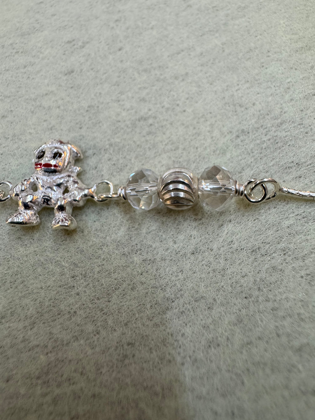 Close view of the faceted beads and the fluted silver rondelle above the enamelled figure charm.