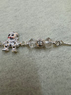 Close view of the faceted beads and the fluted silver rondelle above the enamelled figure charm.