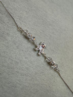The sterling silver bracelet laid out straight, showing the central figure charm between two bead stations on a fine flat chain.