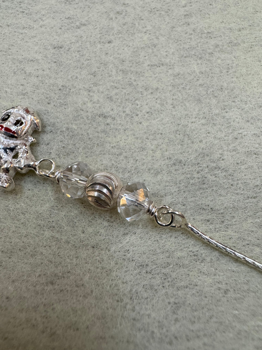 Detail of the fine flat sterling silver chain running into the wire-wrapped bead station above the charm.