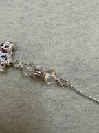 Detail of the fine flat sterling silver chain running into the wire-wrapped bead station above the charm.