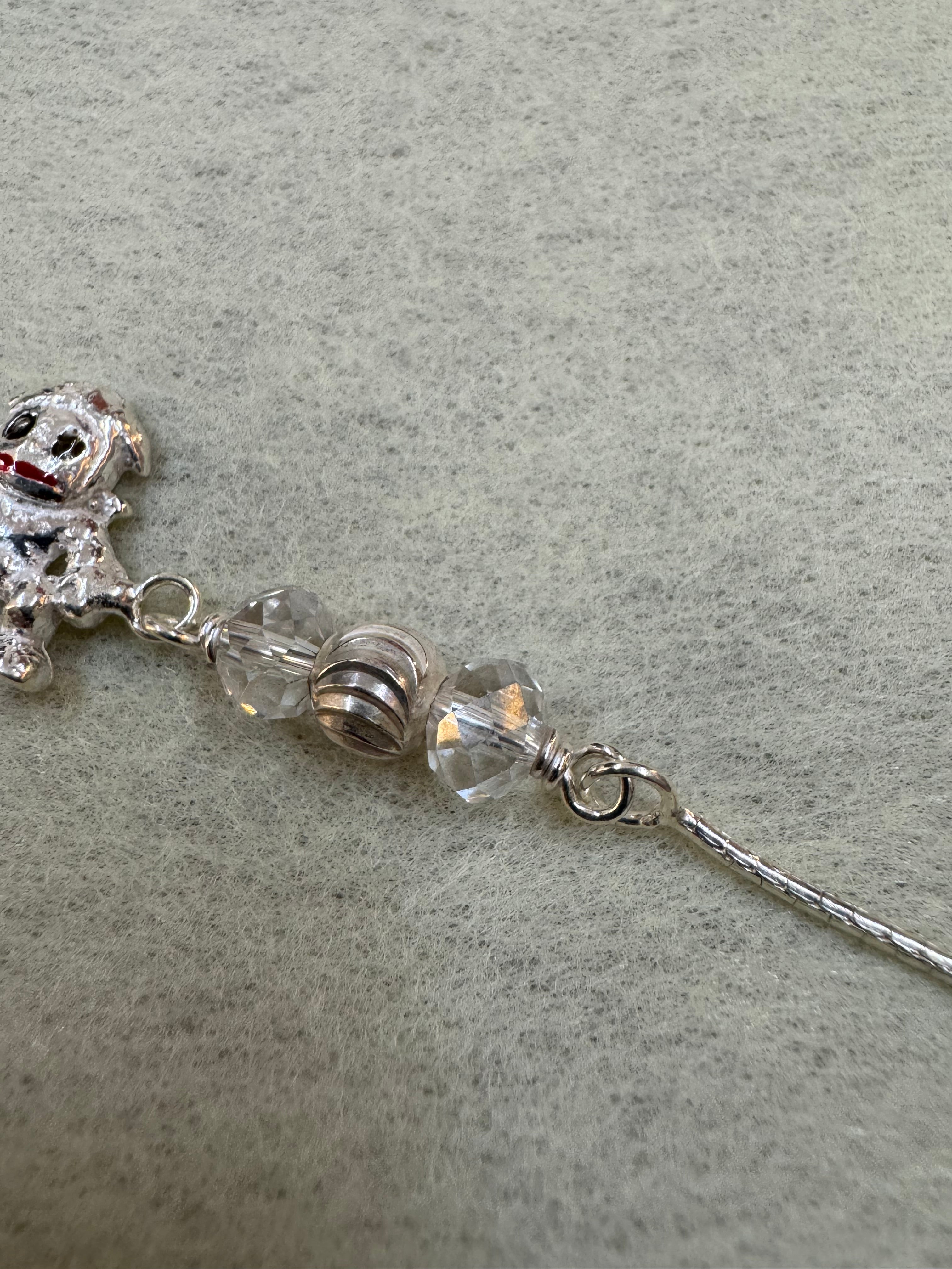 Detail of the fine flat sterling silver chain running into the wire-wrapped bead station above the charm.