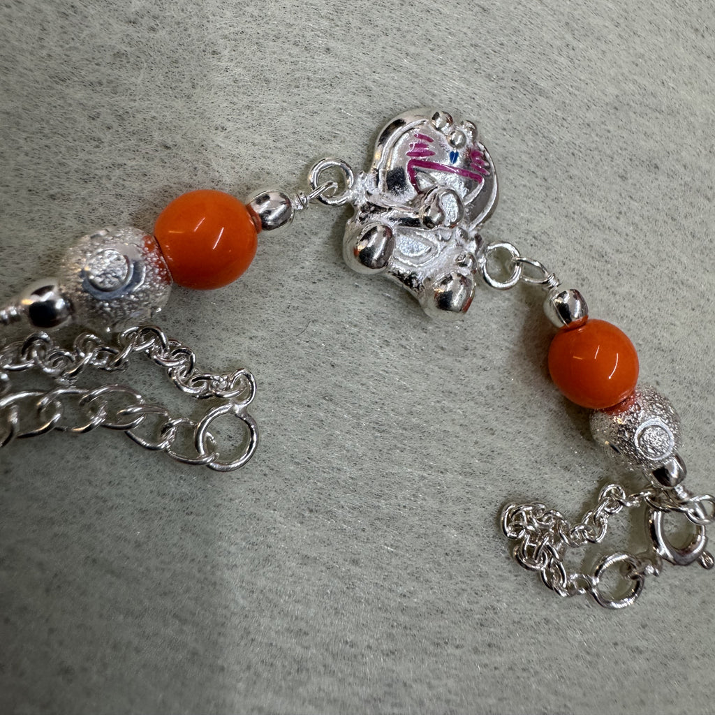 Sterling silver bracelet with a cast enamelled cat, orange beads and granulated silver balls on a rolo chain.