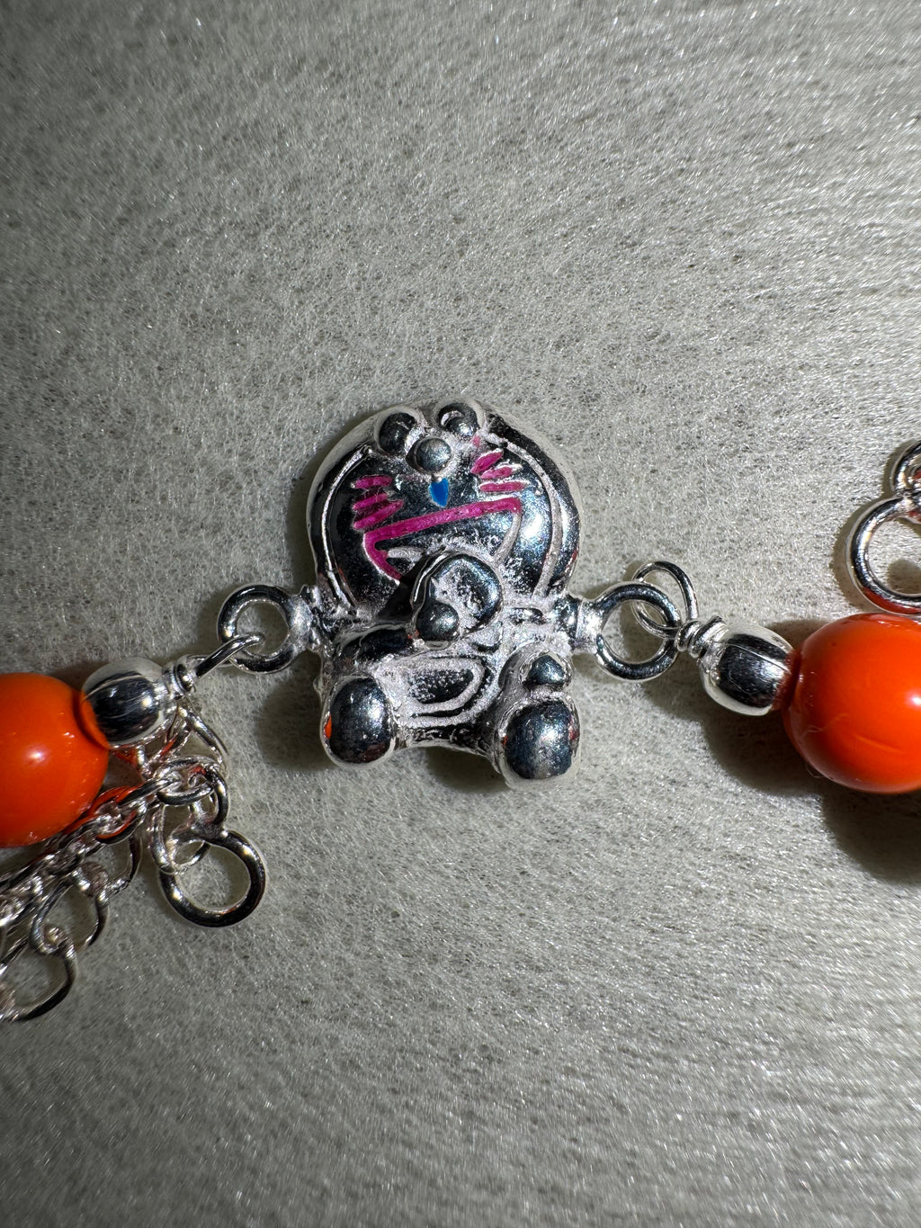 Close view of the cast cat on the sterling silver bracelet, with pink enamel whiskers and a blue enamel nose.