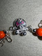 Close view of the cast cat on the sterling silver bracelet, with pink enamel whiskers and a blue enamel nose.