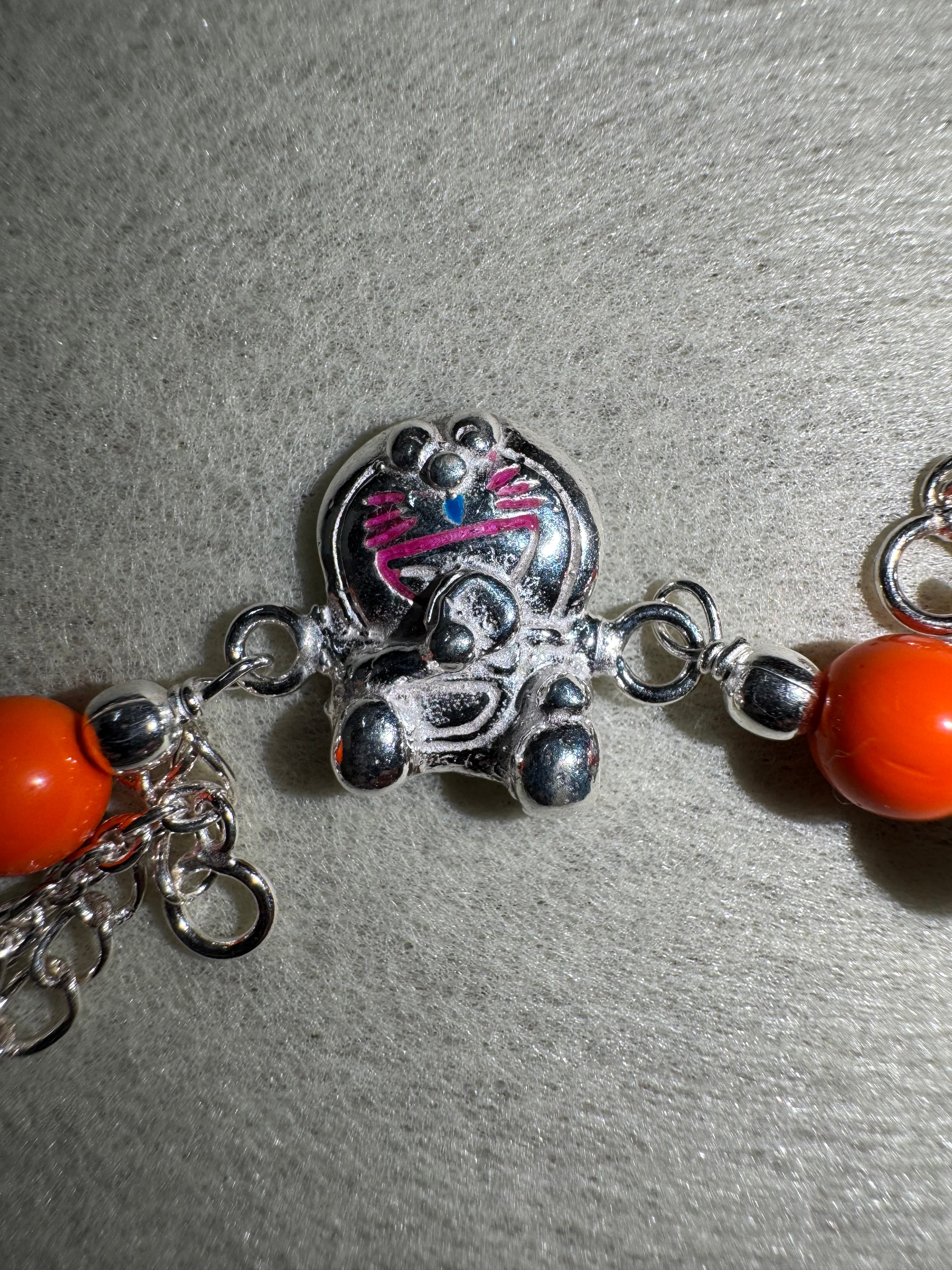 Close view of the cast cat on the sterling silver bracelet, with pink enamel whiskers and a blue enamel nose.
