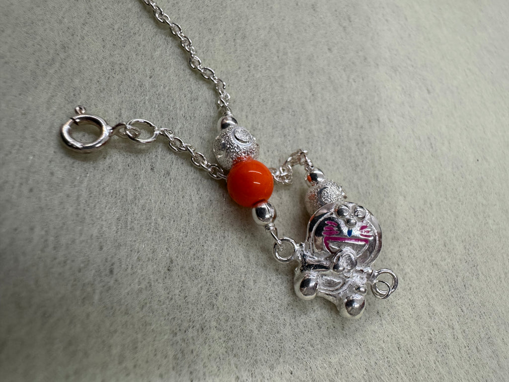The cat station and one orange bead on a fine sterling silver chain, with the spring ring clasp open to the right.