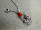 The cat station and one orange bead on a fine sterling silver chain, with the spring ring clasp open to the right.