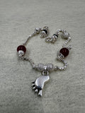 Sterling silver box chain bracelet with a cast baby foot charm, granulated silver balls and dark red capped beads.