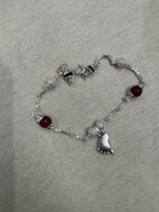 The sterling silver baby foot bracelet opened into a loop on grey felt, showing the spring ring clasp and the spacing of the stations.