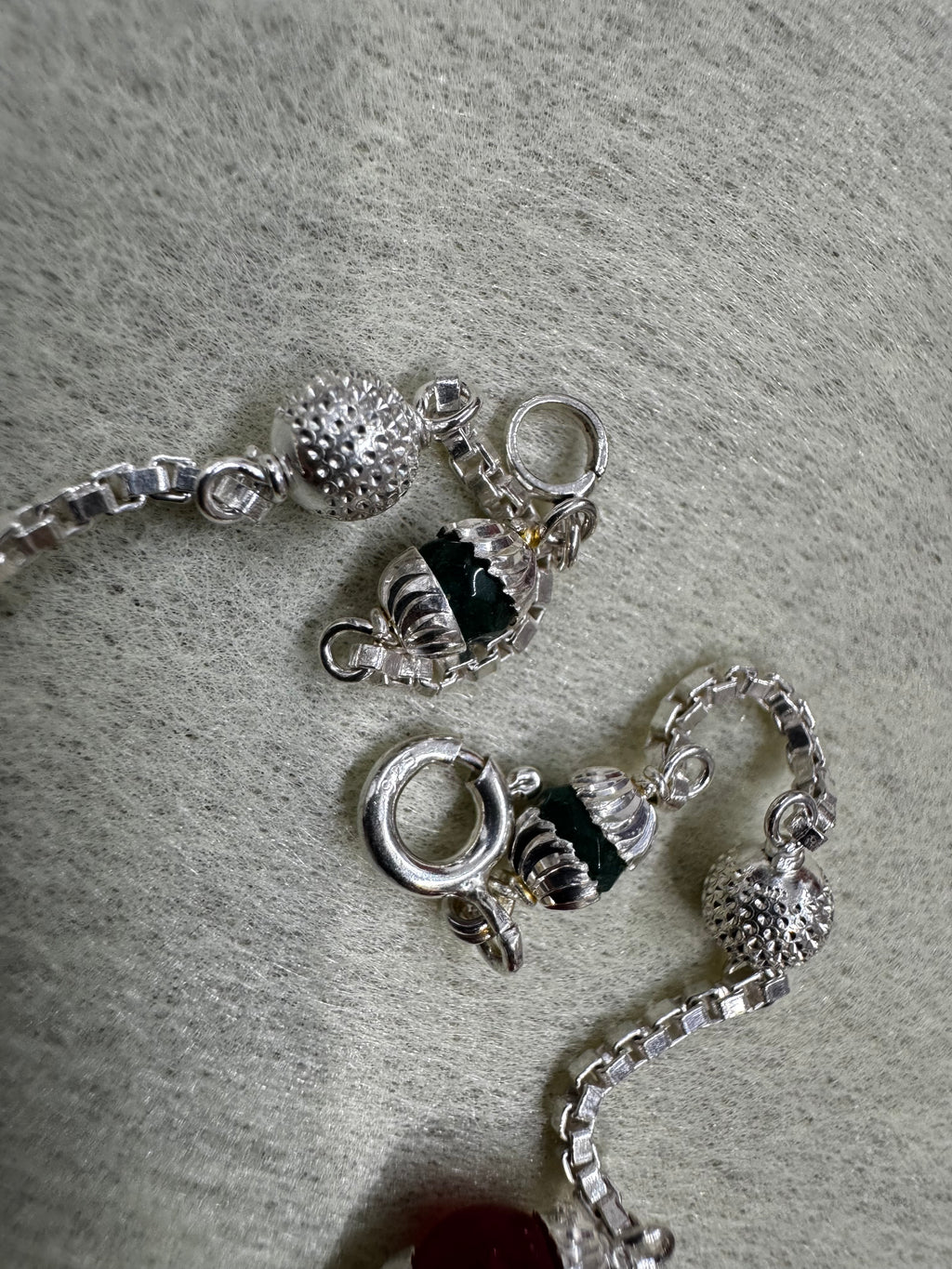 Detail of the spring ring clasp, a dark capped bead and the square links of the sterling silver box chain.