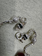 Detail of the spring ring clasp, a dark capped bead and the square links of the sterling silver box chain.