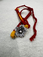 The sterling silver flower bracelet coiled on white felt, with the cotton ties looped to the left.