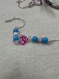 Sterling silver beaded bracelet with blue beads, fluted silver rondelles and a magenta enamel Om motif, laid on grey felt.