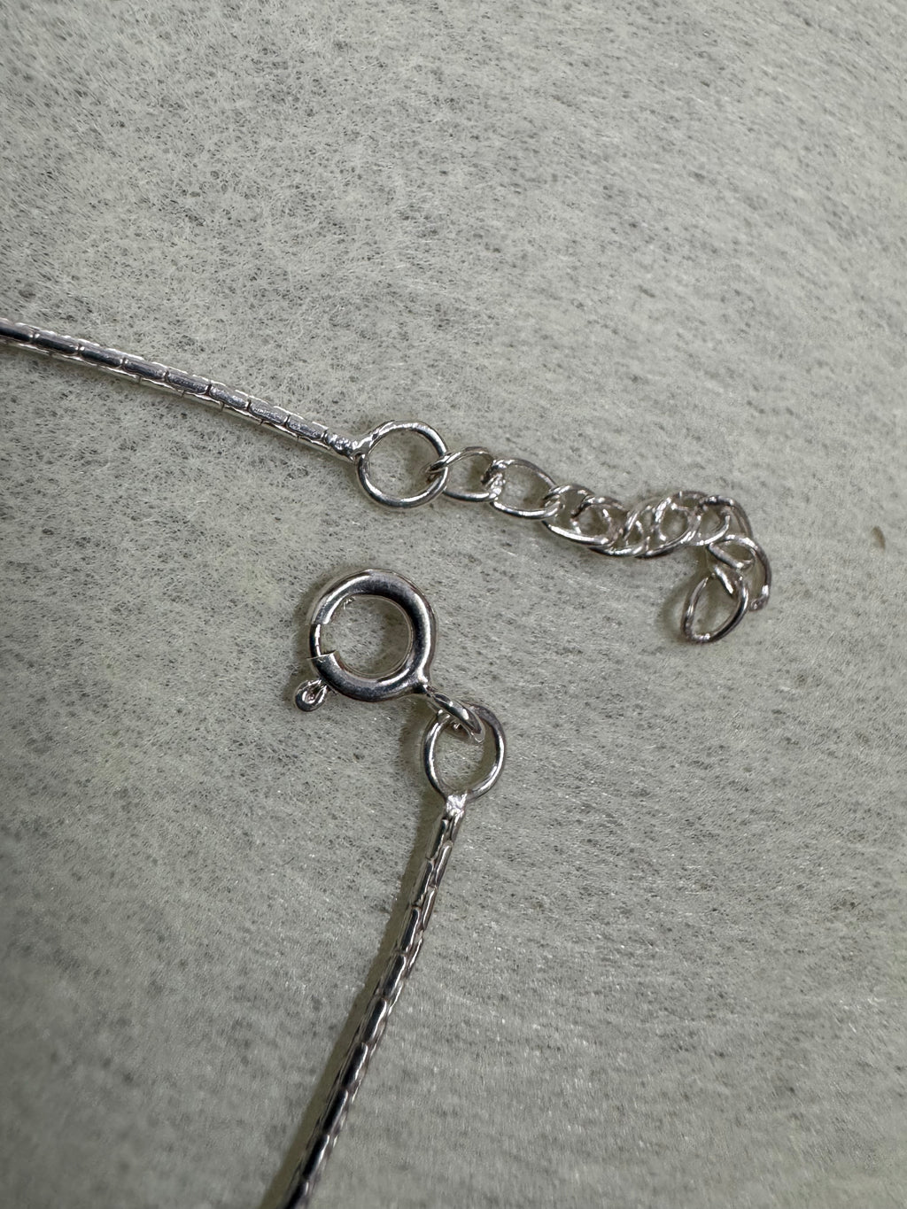 Spring ring clasp and short extender chain on the sterling silver bracelet, with the fine diamond-cut chain running to each side.