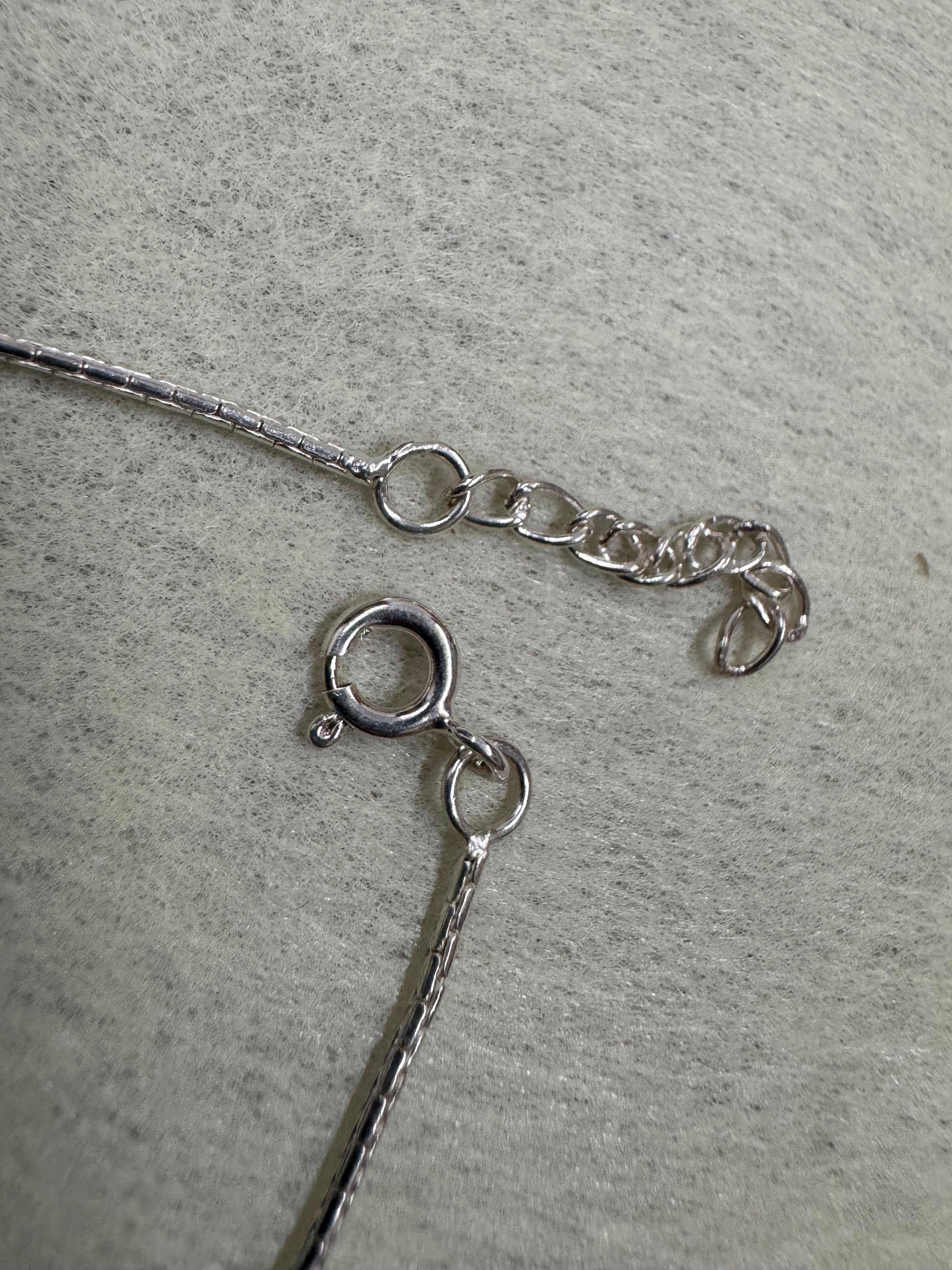 Spring ring clasp and short extender chain on the sterling silver bracelet, with the fine diamond-cut chain running to each side.