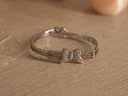 The butterfly bracelet standing upright, showing the rose-tone bars between the silver rails.