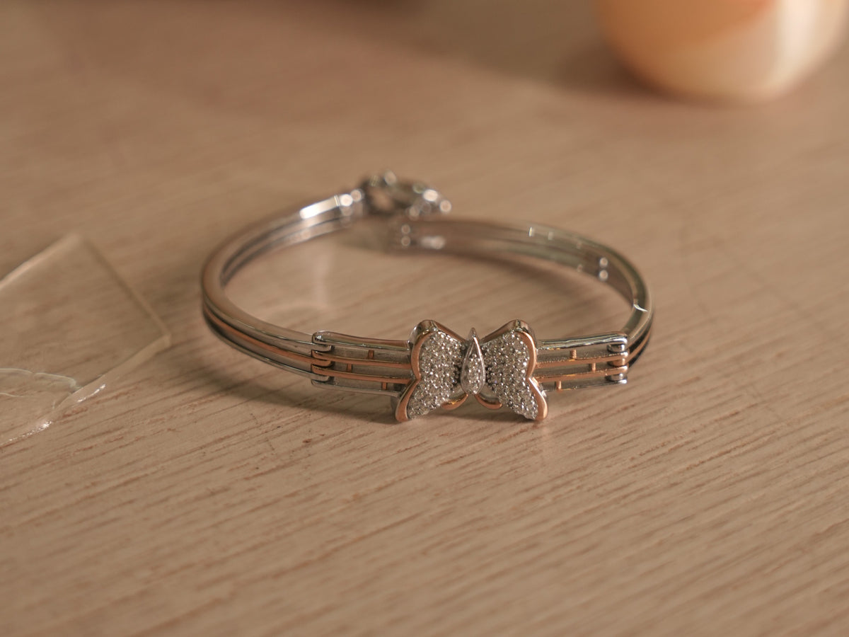 The butterfly bracelet standing upright, showing the rose-tone bars between the silver rails.
