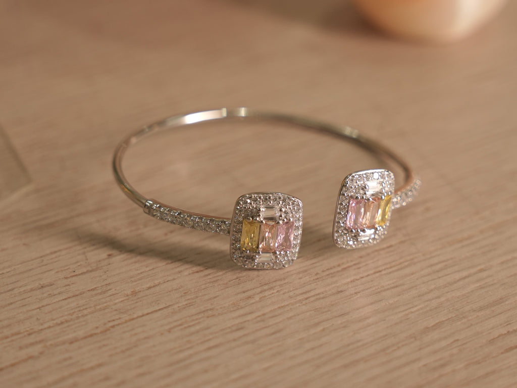 Close view of a pastel baguette cluster on the silver cuff, framed by a pave halo.
