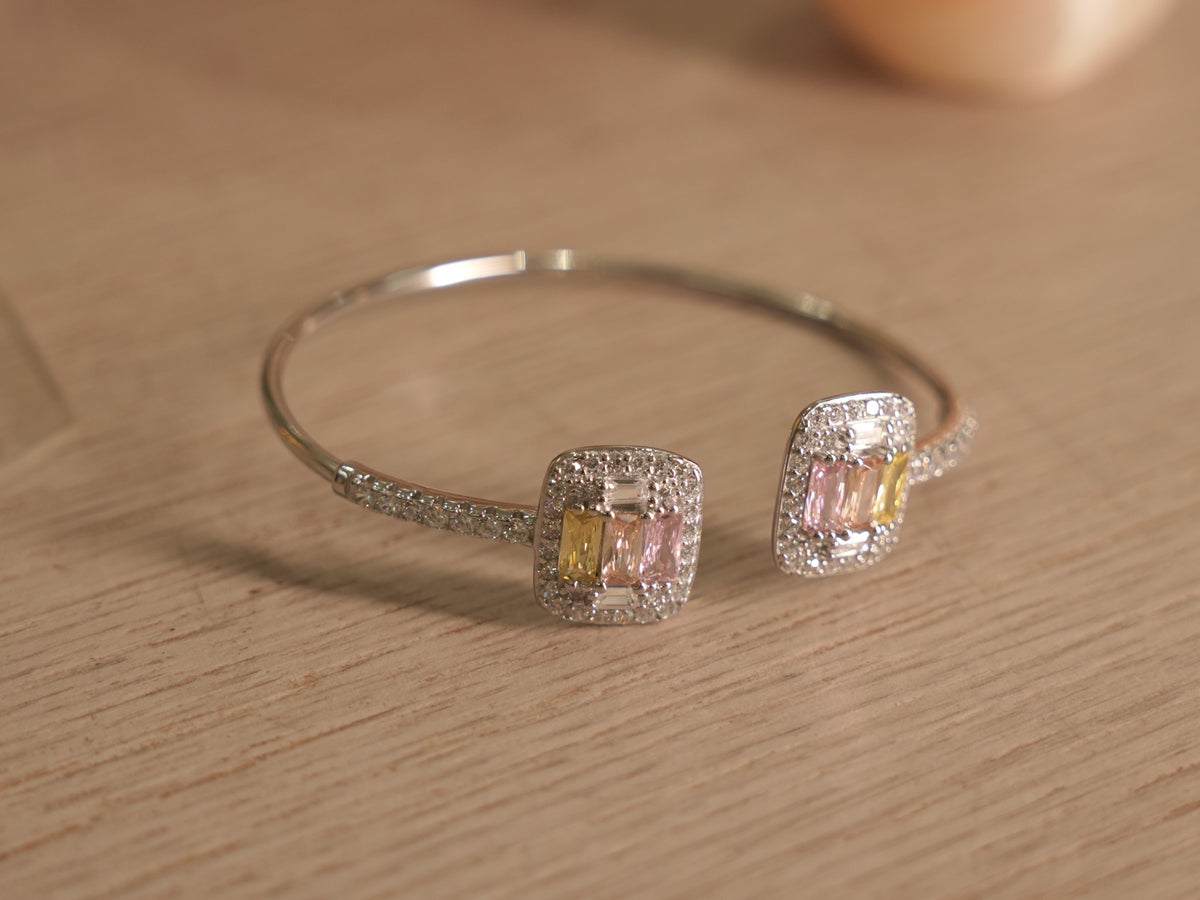 Close view of a pastel baguette cluster on the silver cuff, framed by a pave halo.