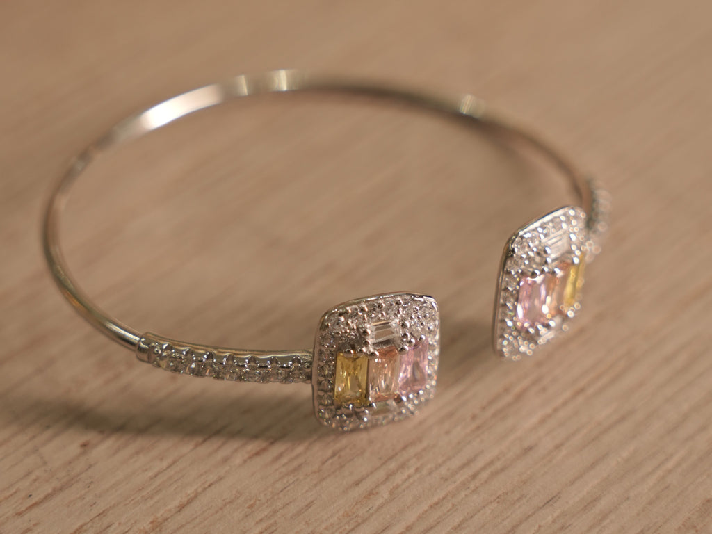 The open cuff bracelet at an angle, showing the two clusters passing each other at the opening.
