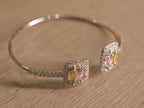 The open cuff bracelet at an angle, showing the two clusters passing each other at the opening.