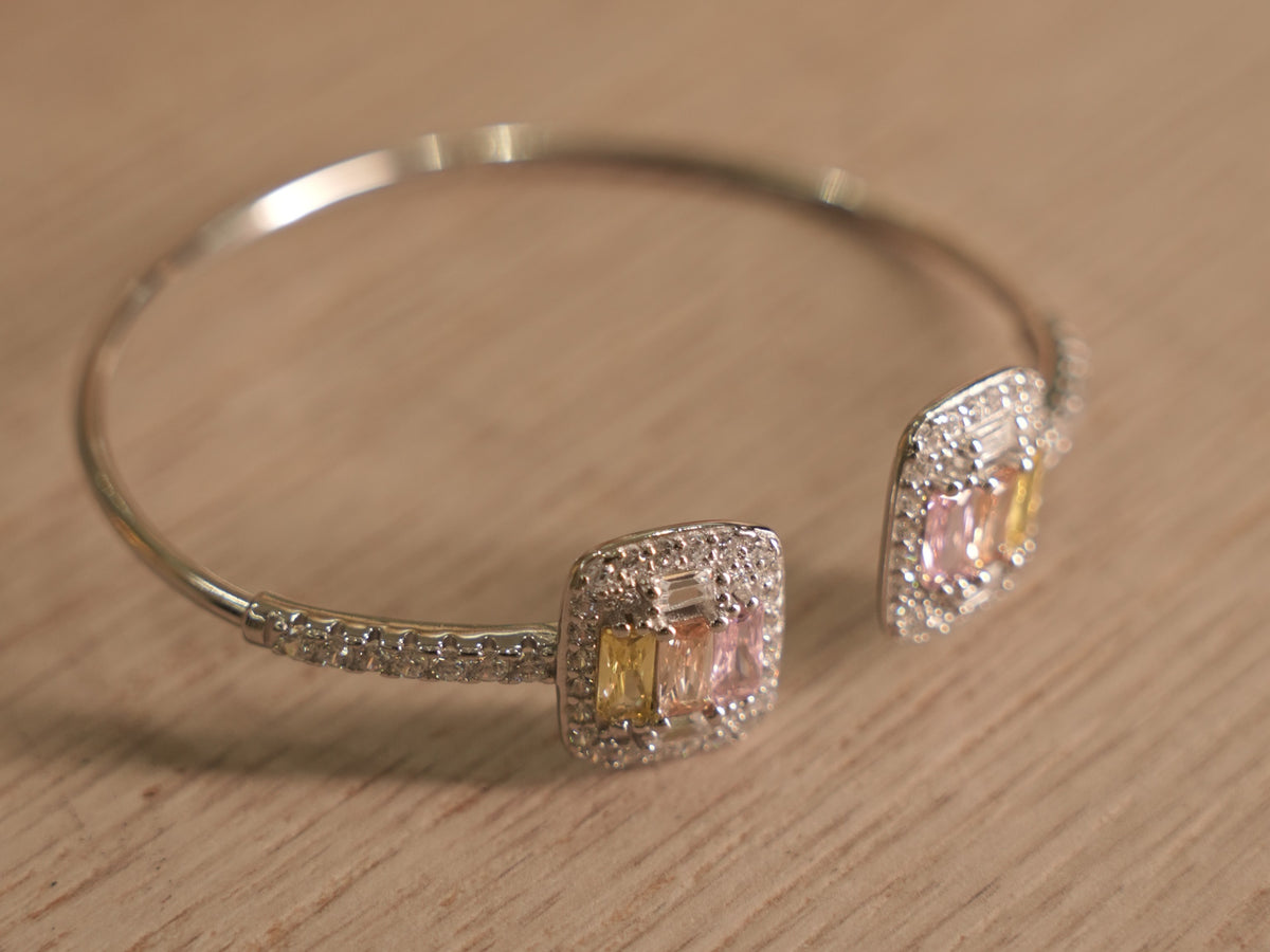 The open cuff bracelet at an angle, showing the two clusters passing each other at the opening.