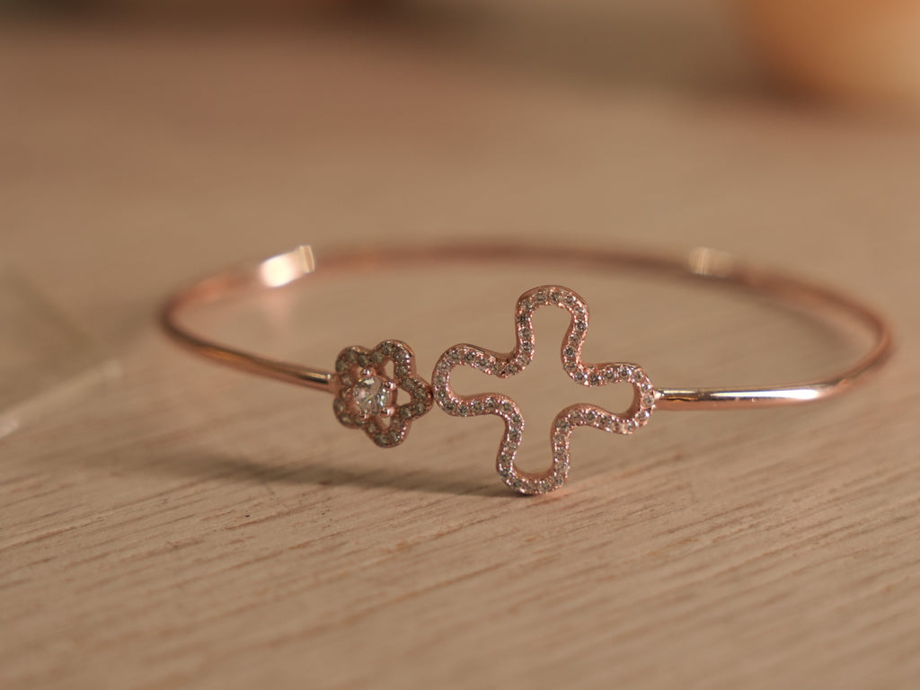 Slim rose-tone wire bracelet with an open clover outline traced in American Diamonds and a small pave flower.