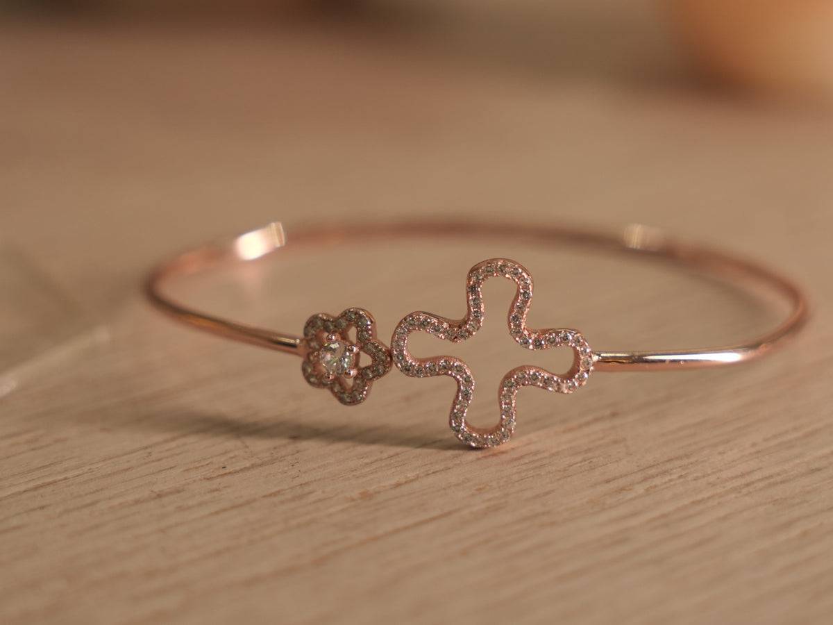 Slim rose-tone wire bracelet with an open clover outline traced in American Diamonds and a small pave flower.