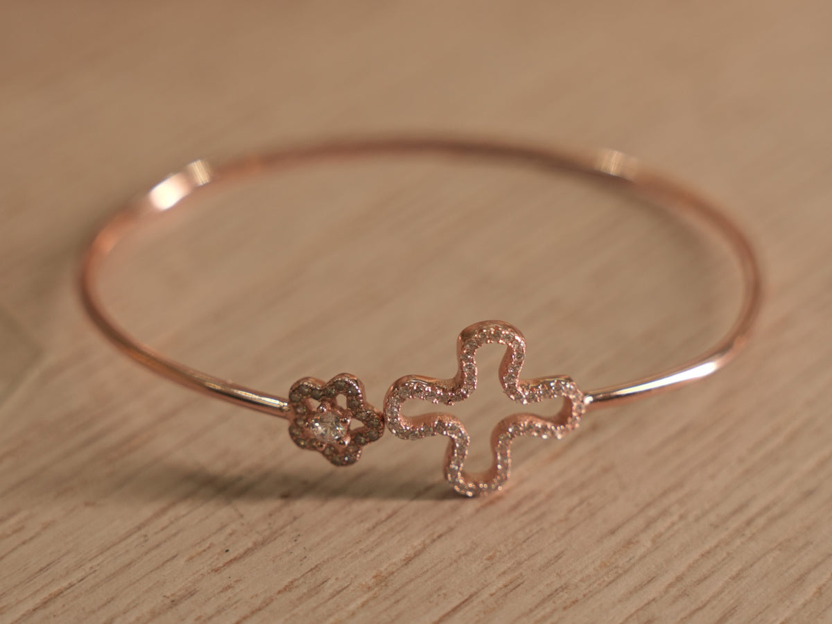 Close view of the clover outline and flower on the rose-tone bracelet wire.