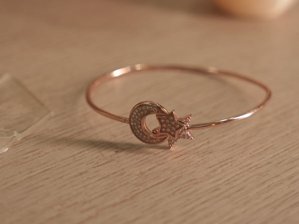 Slim rose-tone wire bracelet with a pave set American Diamonds crescent moon curled around a star.