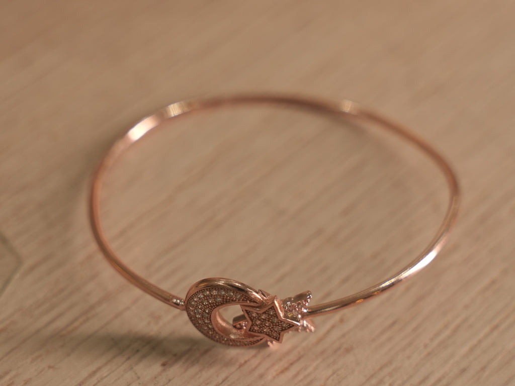 Close view of the crescent and star motif on the rose-tone bracelet.