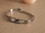 Two-tone sterling silver bracelet with gold-tone lines and a tulip centre holding a deep blue marquise stone.