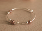 Flexible silver snake chain bracelet with polished silver beads, rose-tone beads and a small heart.