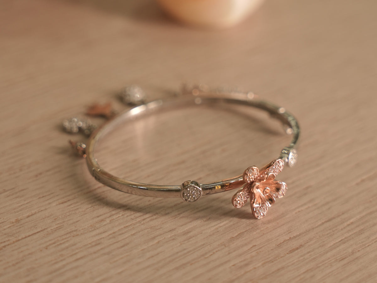 Slim sterling silver bracelet with sculpted rose-tone lilies and pave set American Diamonds discs.