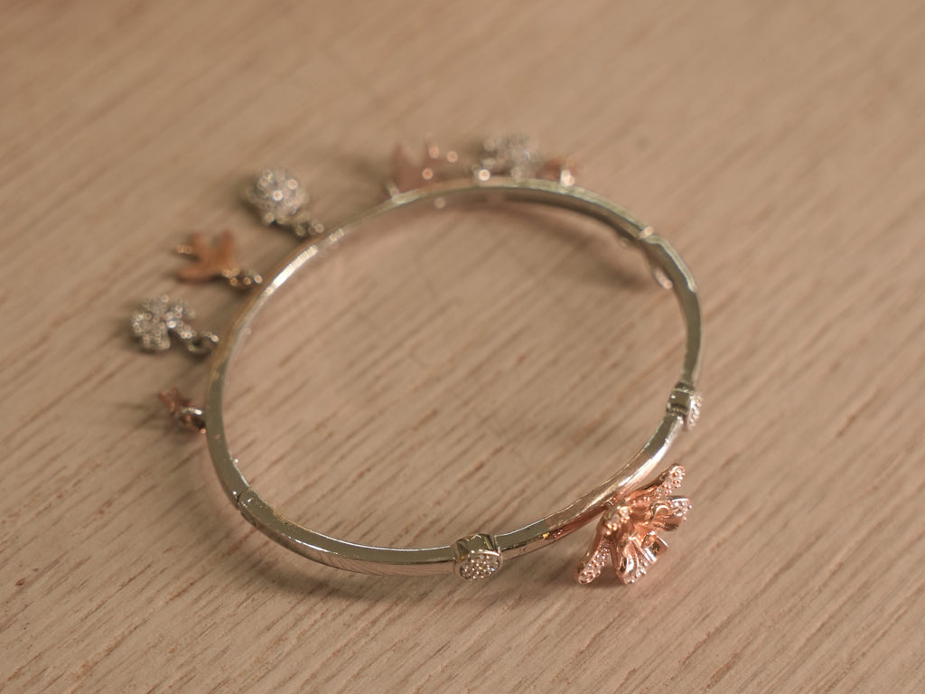 Close view of a rose-tone lily with pave set petals on the silver bracelet.